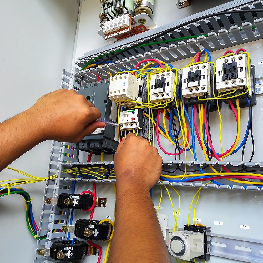 Technician wiring protection and control components inside an electrical cabinet